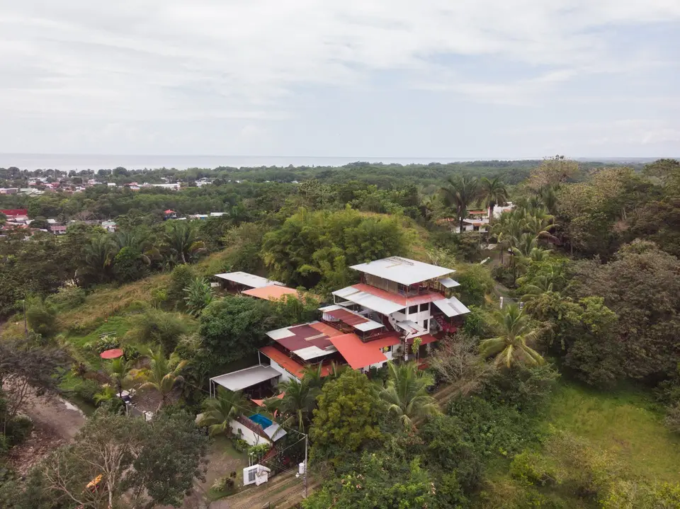 Drone view of the hotel in its green valley, with Quepos and the Pacific on the horizon