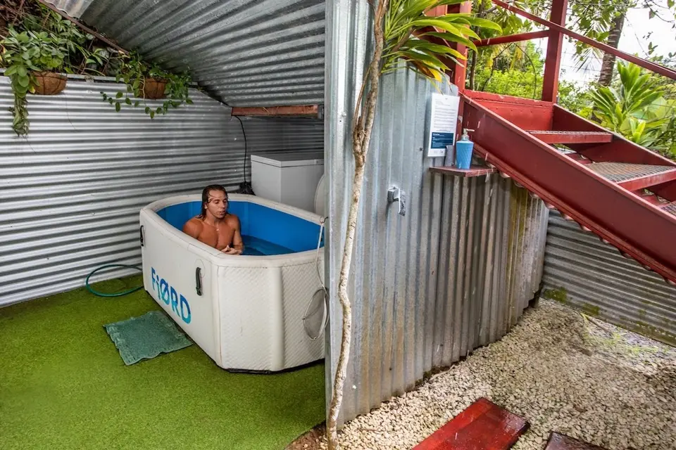 A guest soaking in the two-person cold plunge under a tin roof