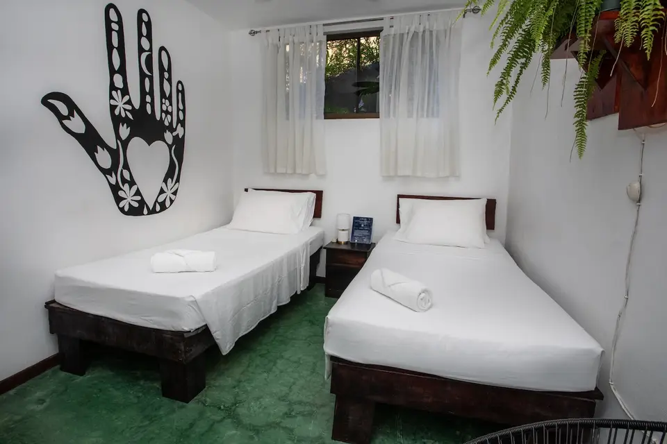 Villa Escondido (Room 5): two twin beds below a painted hand on the wall