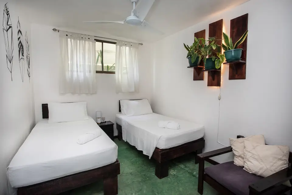 Villa Escondido: twin beds side by side under a window with sheer curtains