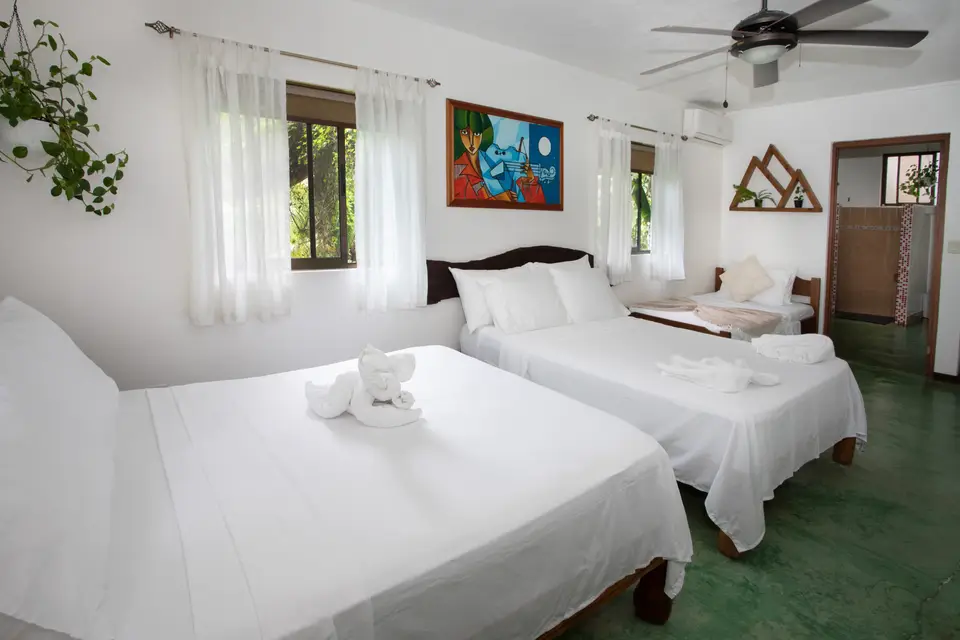 Villa Fresca: two double beds in a bright white room with a ceiling fan