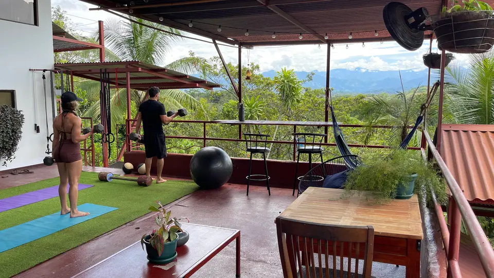 The rooftop gym: guests exercising on the turf, jungle and mountains beyond