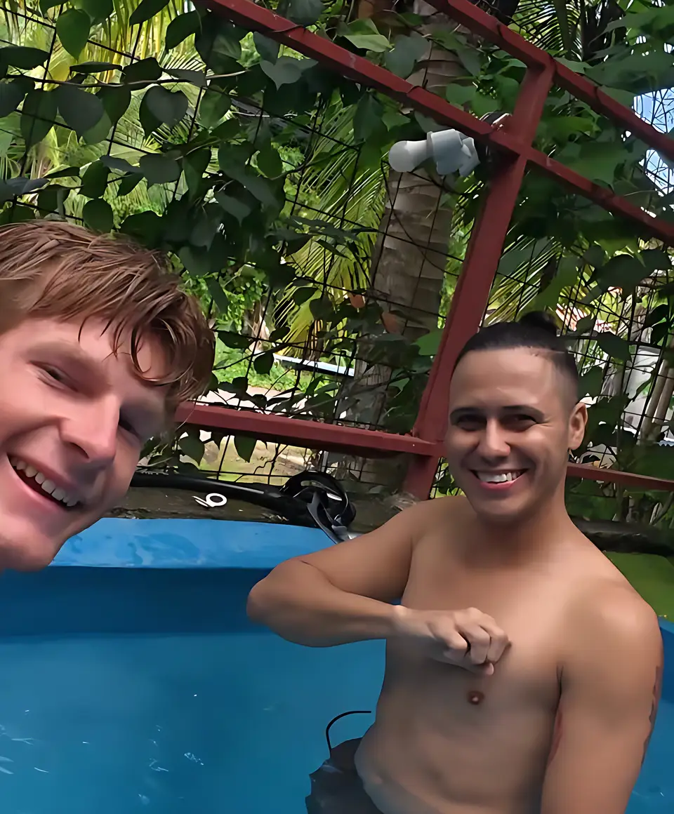 Two guests laughing in the blue cold-plunge tub under the red frame