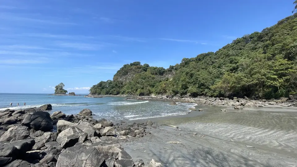 Playa La Macha: a small rocky beach below a green headland
