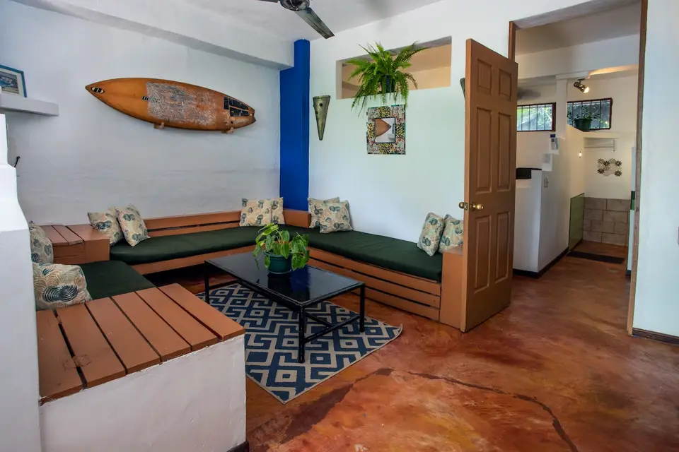 Villa Luna’s living room: sofa, coffee table and a surfboard on the wall