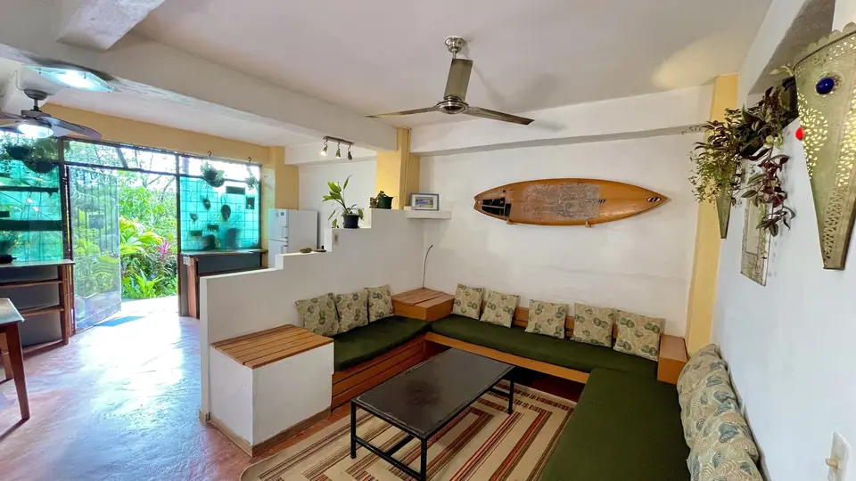 Villa Luna: a built-in sofa with patterned cushions, a surfboard on the wall and the kitchen beyond