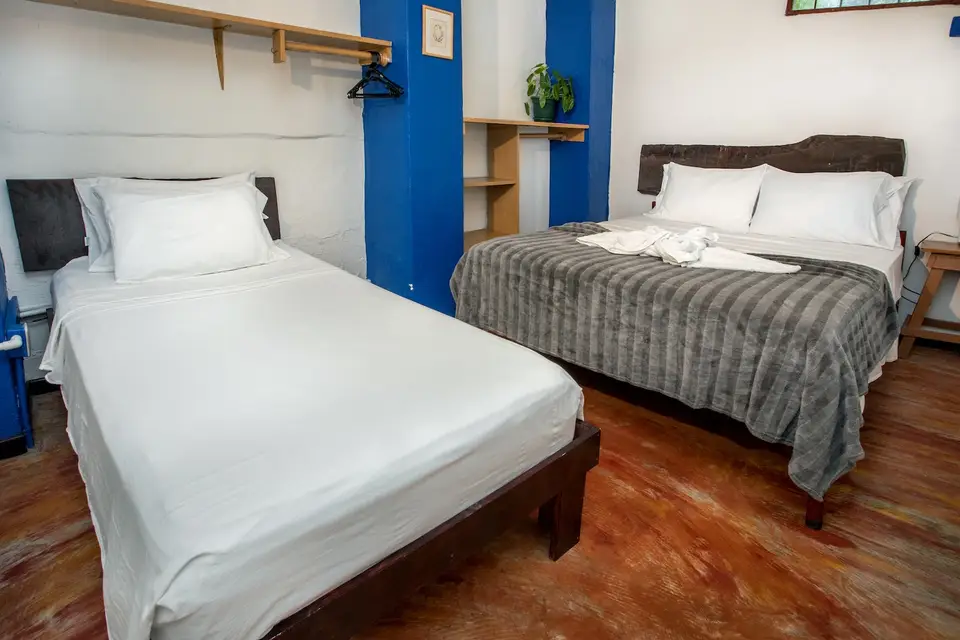 Villa Luna: queen bed with a grey throw and a plant-lined window