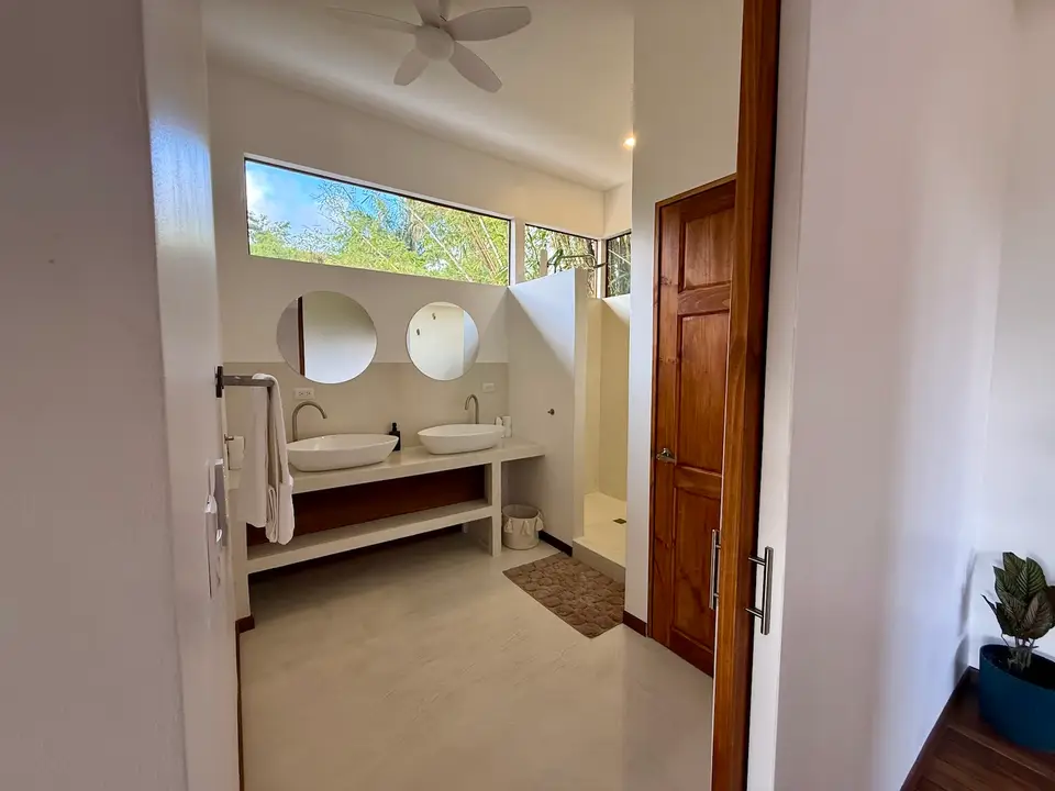 Bird’s Nest Apartment: bathroom with round mirrors and a window to the trees