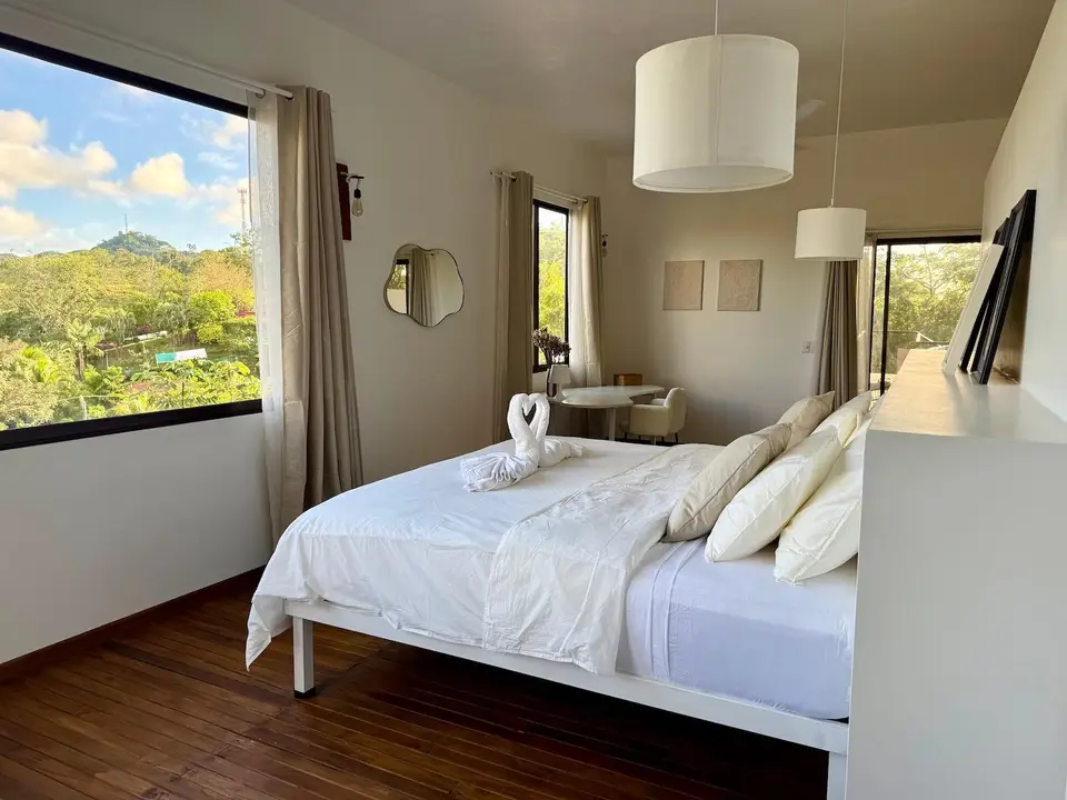 Bird’s Nest Apartment: king bed facing windows full of treetops