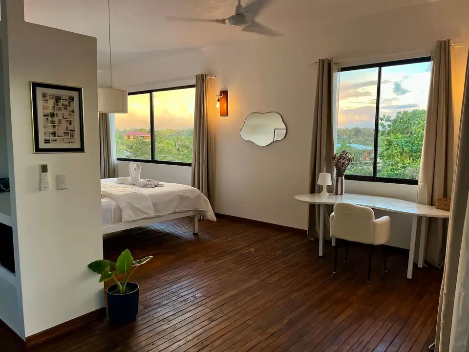 Bird’s Nest Apartment: bed and writing desk under a window onto the jungle