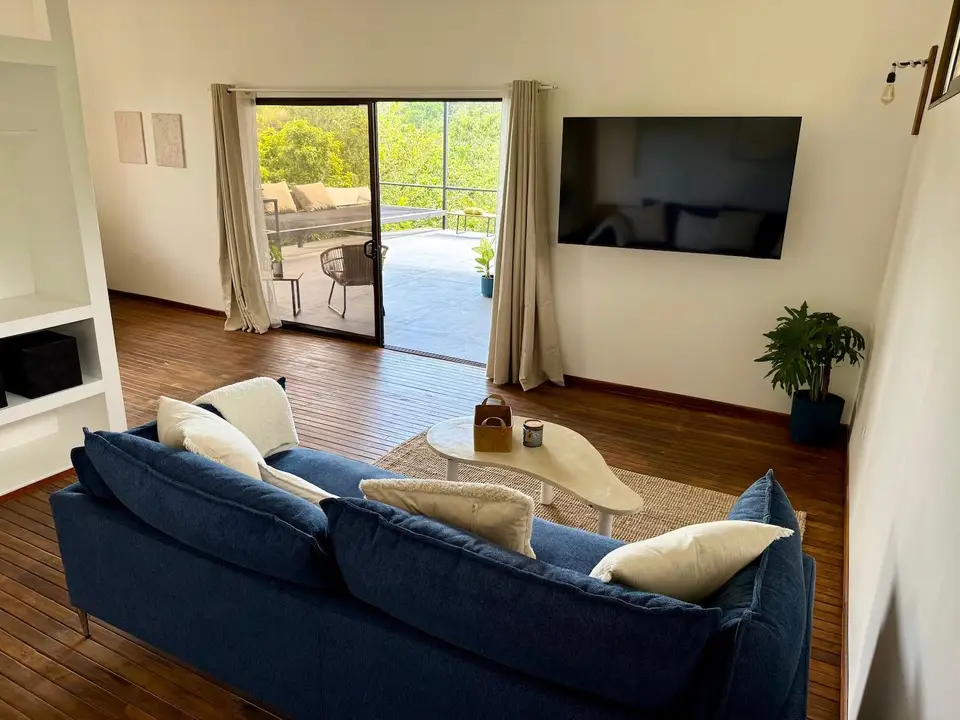 Bird’s Nest Apartment: blue sofa, cushions and a wall-mounted TV