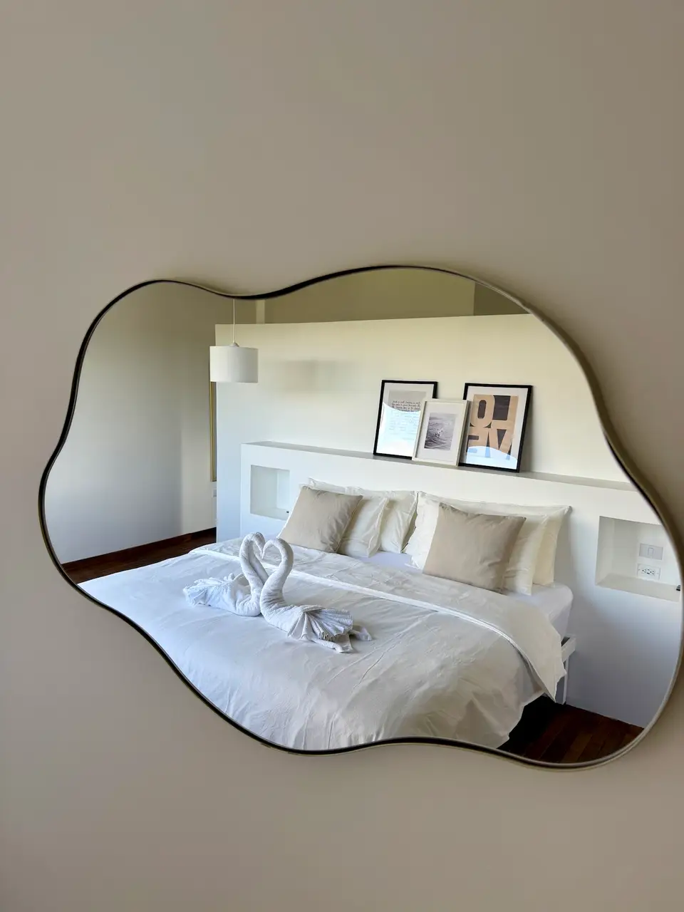 Bird’s Nest Apartment: the bed reflected in a wavy wall mirror