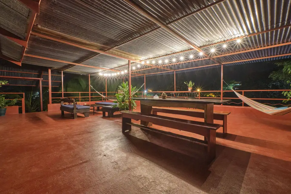 The rooftop at night: string lights over long wooden tables and benches