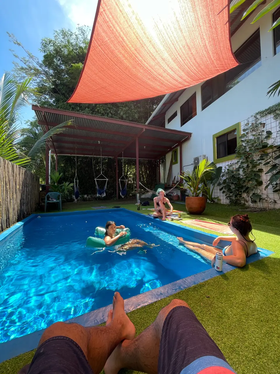 Guests floating in the pool under the orange shade sail