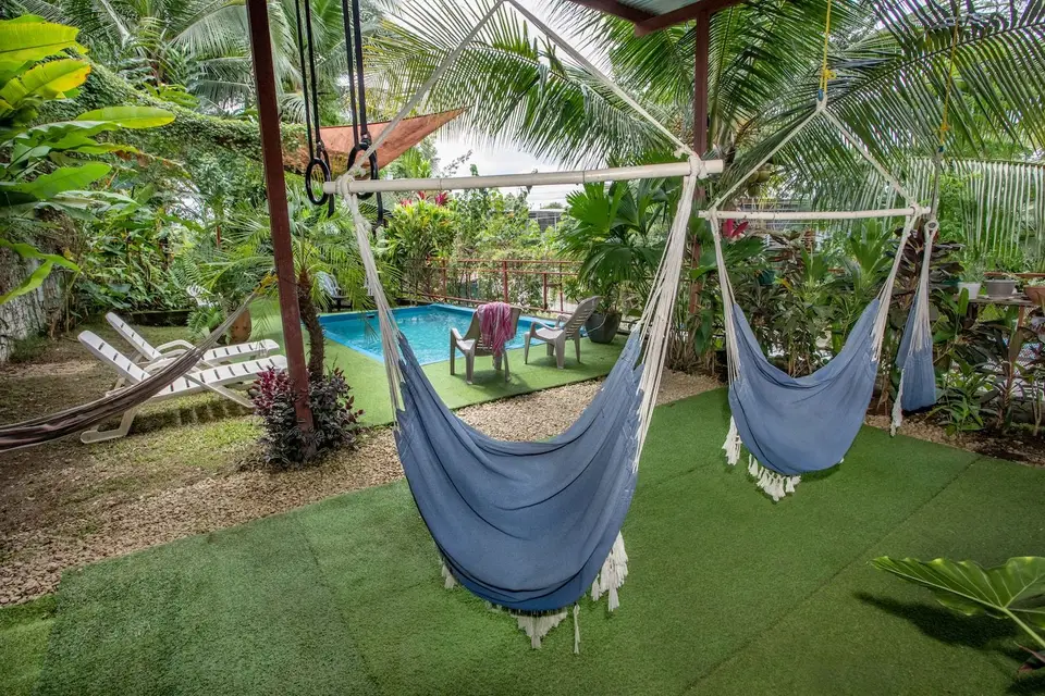 Hammock chairs hanging over the turf beside the pool