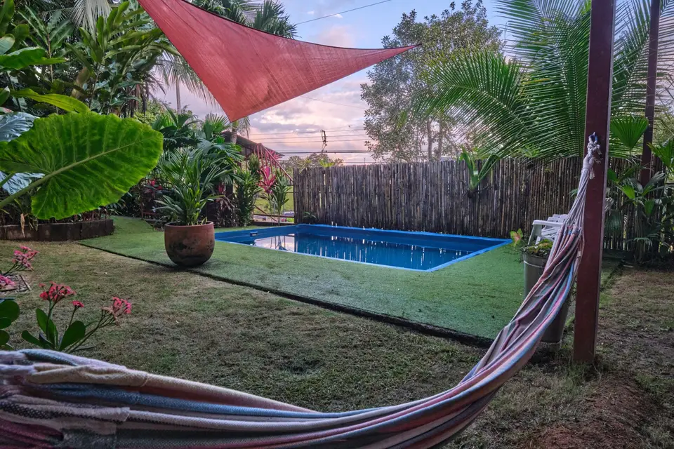 The pool under a terracotta shade sail, a hammock strung along the edge