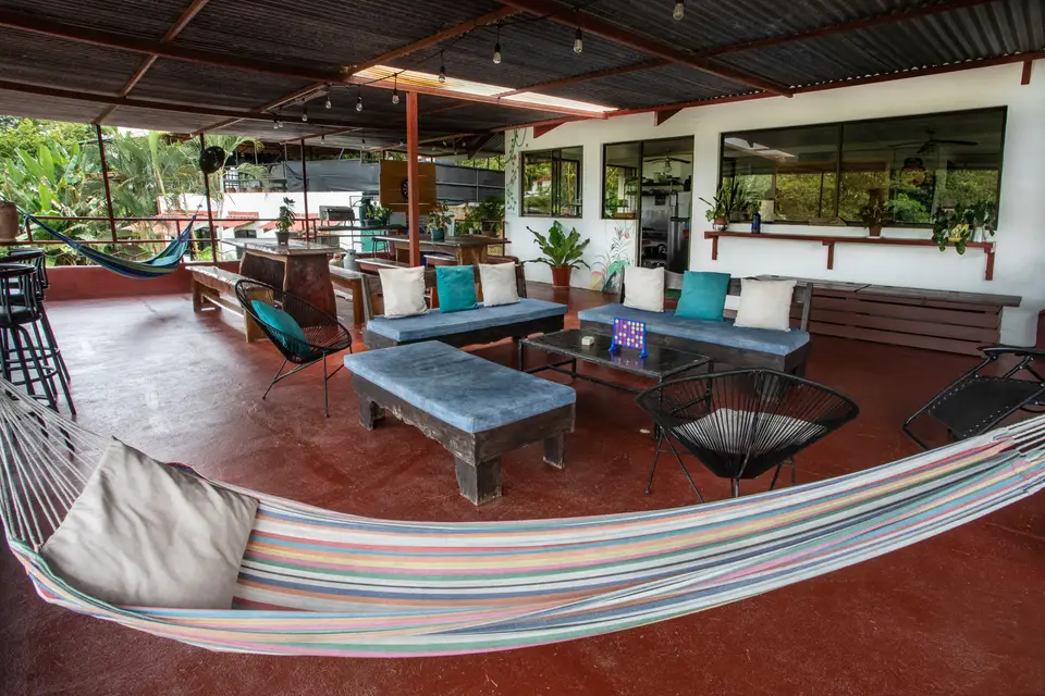The covered reception terrace: a hammock, striped sofas and plants on the red floor