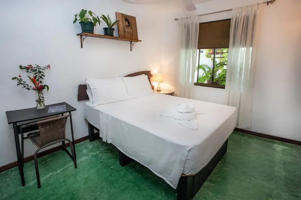 Villa Sol (Room 6): double bed, small desk and a curtained window