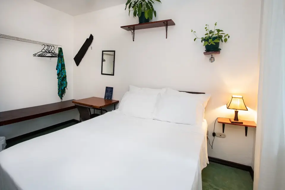 Villa Sol (Room 2): a made double bed, wall art and a shelf of plants