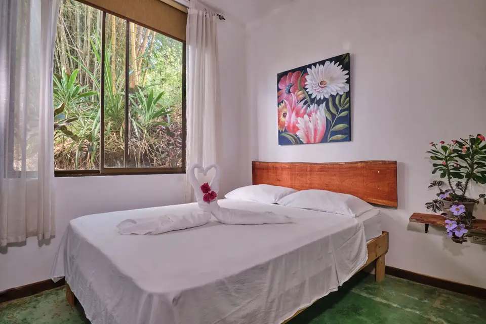Villa Sol: una cama matrimonial con cabecera de madera natural y una pintura de flores