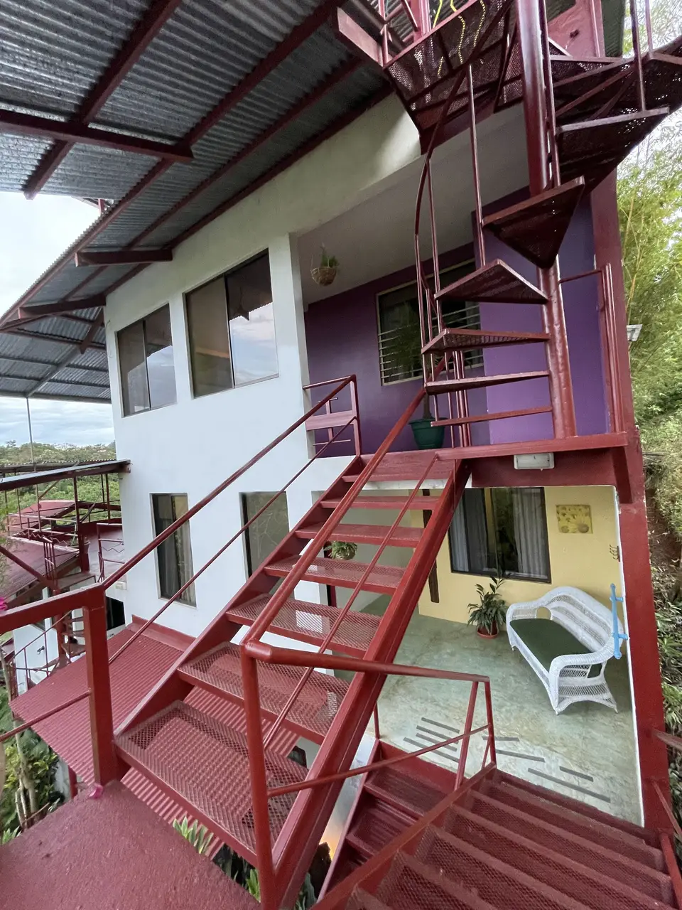 Looking up the red exterior stairways of the building, framed by leaves