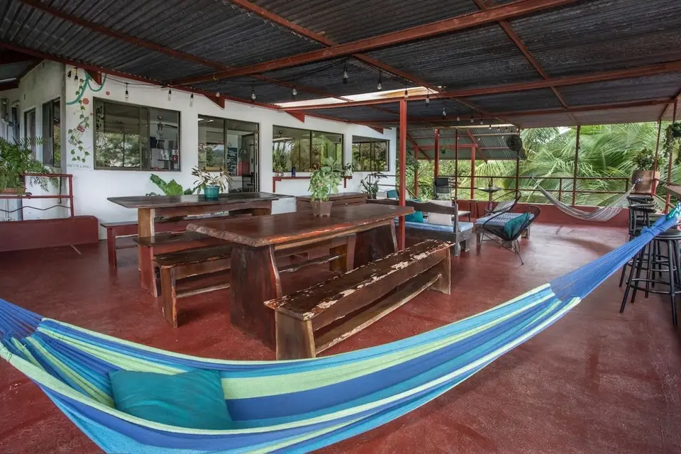 A long wooden community table and a striped hammock on the red terrace