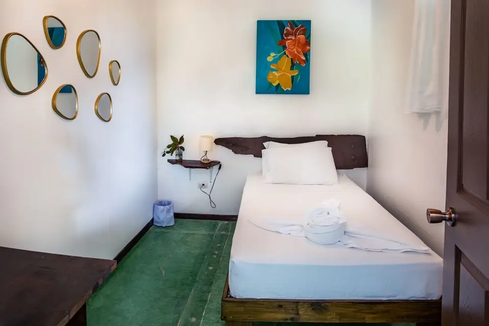 Villa Voluntario: a single bed with a live-edge headboard, gold mirrors and a flower painting