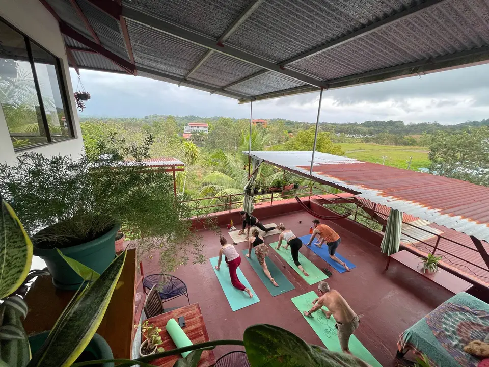A retreat group practising on colourful mats across the red rooftop